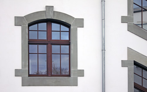 Renovierte, verputzte Fassade mit Fenstergewände und neuem Fenster.