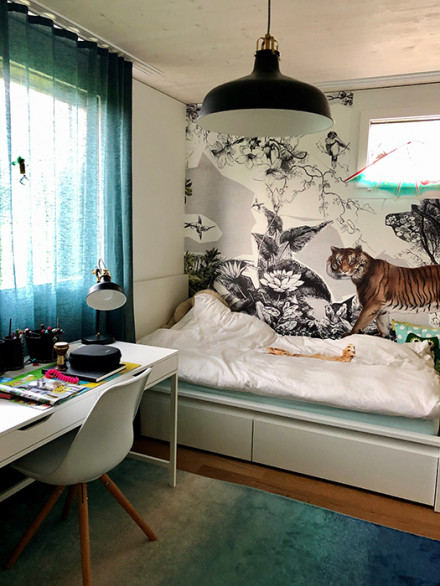 Kinderzimmer mit Arbeitstisch, Bett und Wandtapete mit Tigersujet.