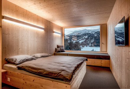 Hotelzimmer mit zwei Betten und einer Coach, die als Bett umfunktioniert werden kann. Durchs Fenster Blick auf den Heidsee.