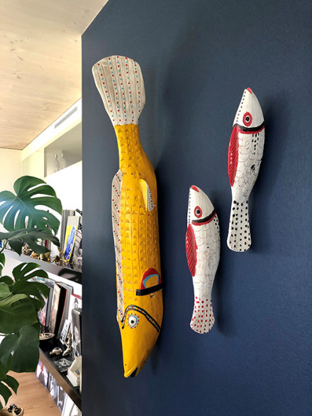 Dunkelblau gestrichene Wand, darauf festgetackert drei Fische aus Pappmaché als Kunstobjekte