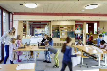 Kinder im Schulzimmer am Lernen mit Papier oder am Laptop.