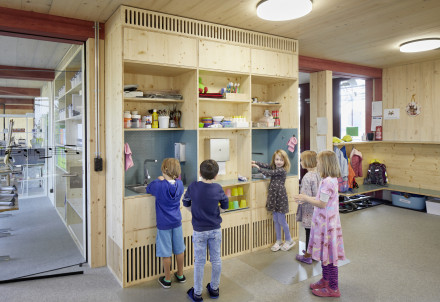 Kinder im Schulzimmer am Händewaschen - viel Holz im Innenausbau ist sichtbar.