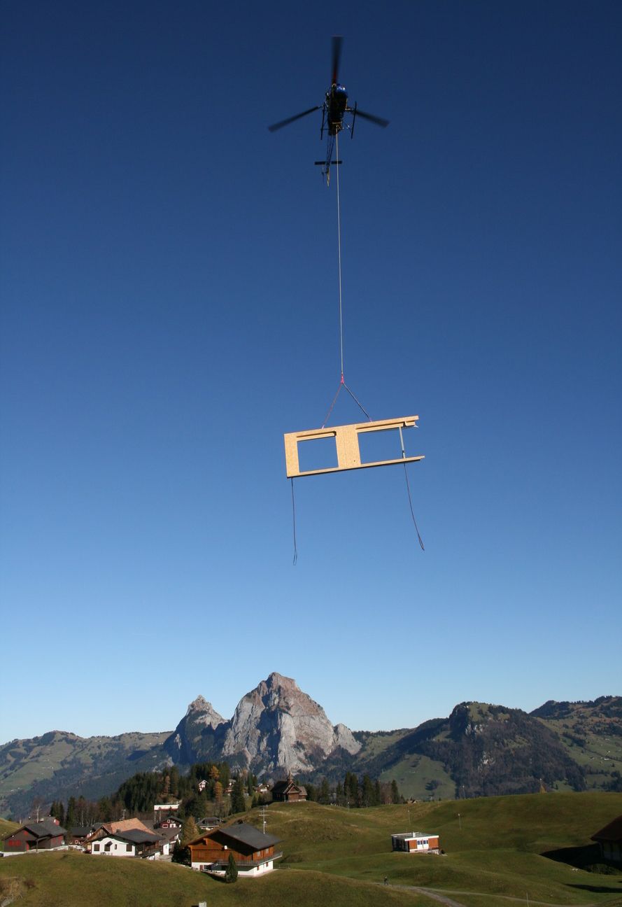 Helikopter fliegt mit baumelndem Wandelement über den Stoos