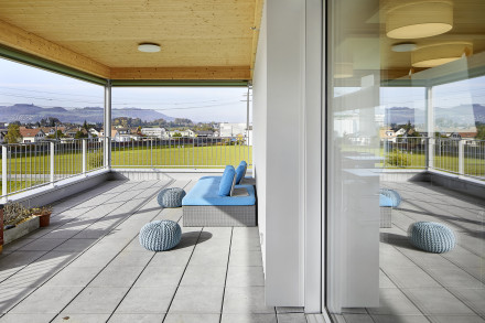 Balkon mit sichtbarem Holz auf der Deckenunterseite und Sitzgelegenheit.