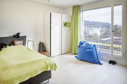 Kinderzimmer mit Bett, Schrank und grossem Fenster