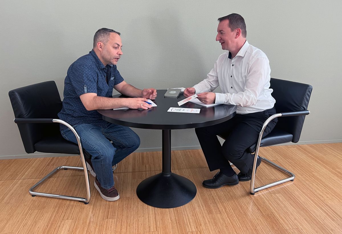 Zwei Personen diskutieren an einem runden Tisch mithilfe von Karten