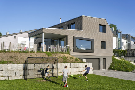 Aussenansicht mit Blick auf die Terrasse und den Garten mit Fussballspielenden Kindern