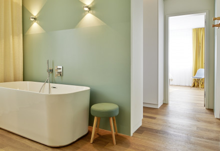 Freistehende Badewanne im Badezimmer mit passender Wandfarbe, Bodenbelag (Parkett) und Vorhang