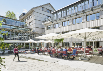 Saniertes Forschungsgebäude in Birmensdorf mit Mitarbeitenden unter Sonnenschirmen im Innenhof bei der Mittagspause im Sommer