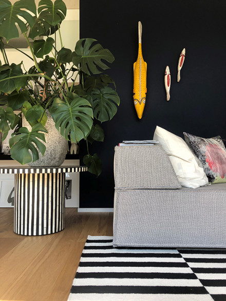 Sofa, Teppich, dunkelblaue Wand mit Kunst und Pflanze