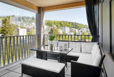 Blick auf die Loggia mit Beschattung, Glasschiebetüren und sichtbarer Holzdecke