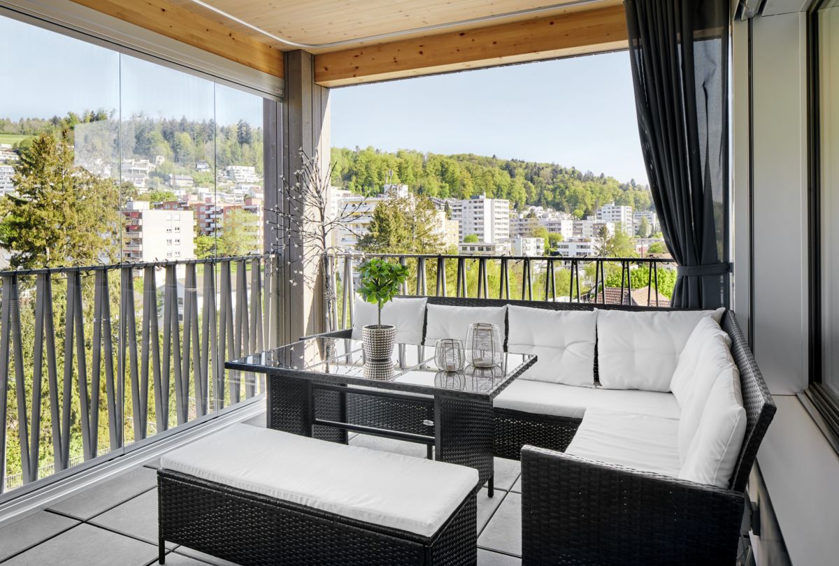 Blick auf die Loggia mit Beschattung, Glasschiebetüren und sichtbarer Holzdecke