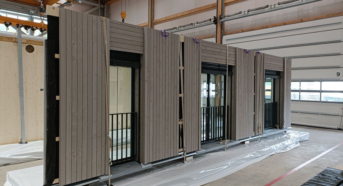 Wandelement mitsamt Fenstern, Laibungen, Fassadenbekleidung, Lisenen, Fensterbänken, Brandschutzblechen sowie vormontierten Geländern und Storen