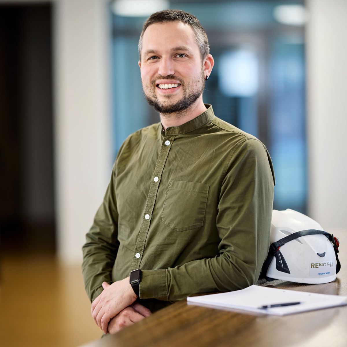 Projektleiter an Stehtisch mit Bauhelm darauf