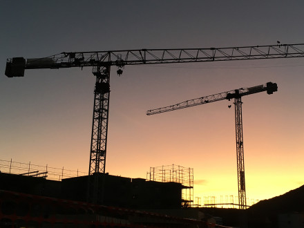 Atmosphère matinale sur le chantier, avec deux grues.