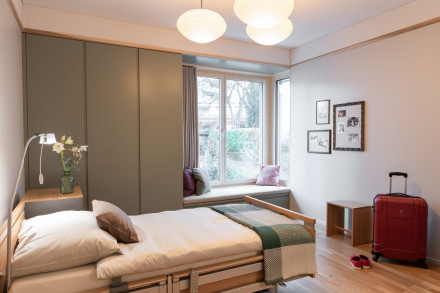 Chambres de l'hospice avec des matériaux chauds et des tons de couleurs ainsi que des sièges confortables avec fenêtre