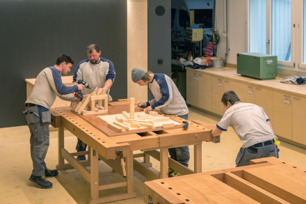 Des apprentis en train de réaliser des maquettes sur un grand établi