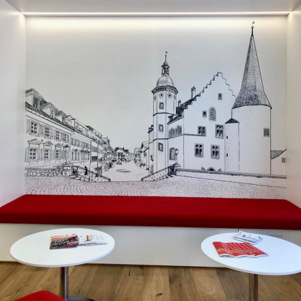 Un détail de l‘entrée de l’agence de la Mobilière avec un papier peint représentant, sous forme de dessin, la petite ville de Sursee.