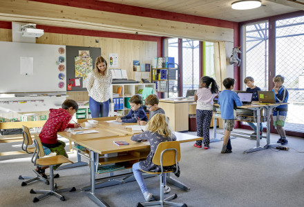 Enfants assis à deux îlots de tables groupées en train d'apprendre