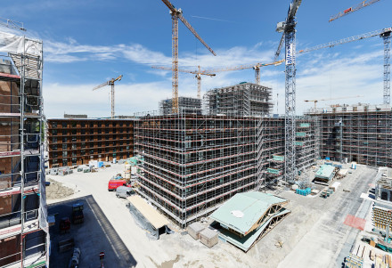 Chantier du bâtiment en bois avec l’échafaudage et le toit de secours au premier plan.