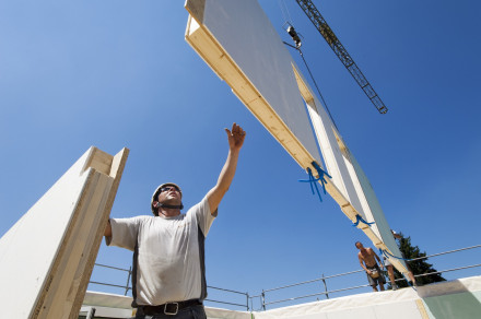 Charpentier en train de monter un élément de parois en système de construction bois