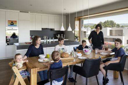 Table de midi avec la famille et les amis avec vue sur la cuisine et la grande fenêtre où l'on peut s'asseoir