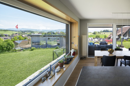 Vue de la cuisine sur la grande fenêtre, la table à manger et la terrasse 