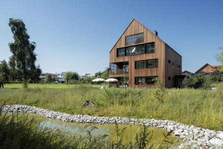 Immeuble d'habitation de quatres étages en bois avec façade en bois, jardin avec étang