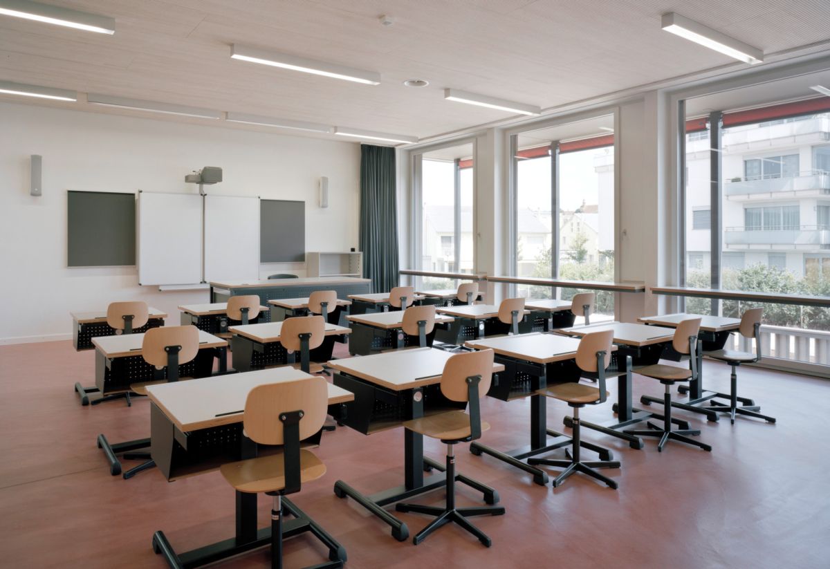 Salle de classe avec baies vitrées et coursive avec stores.