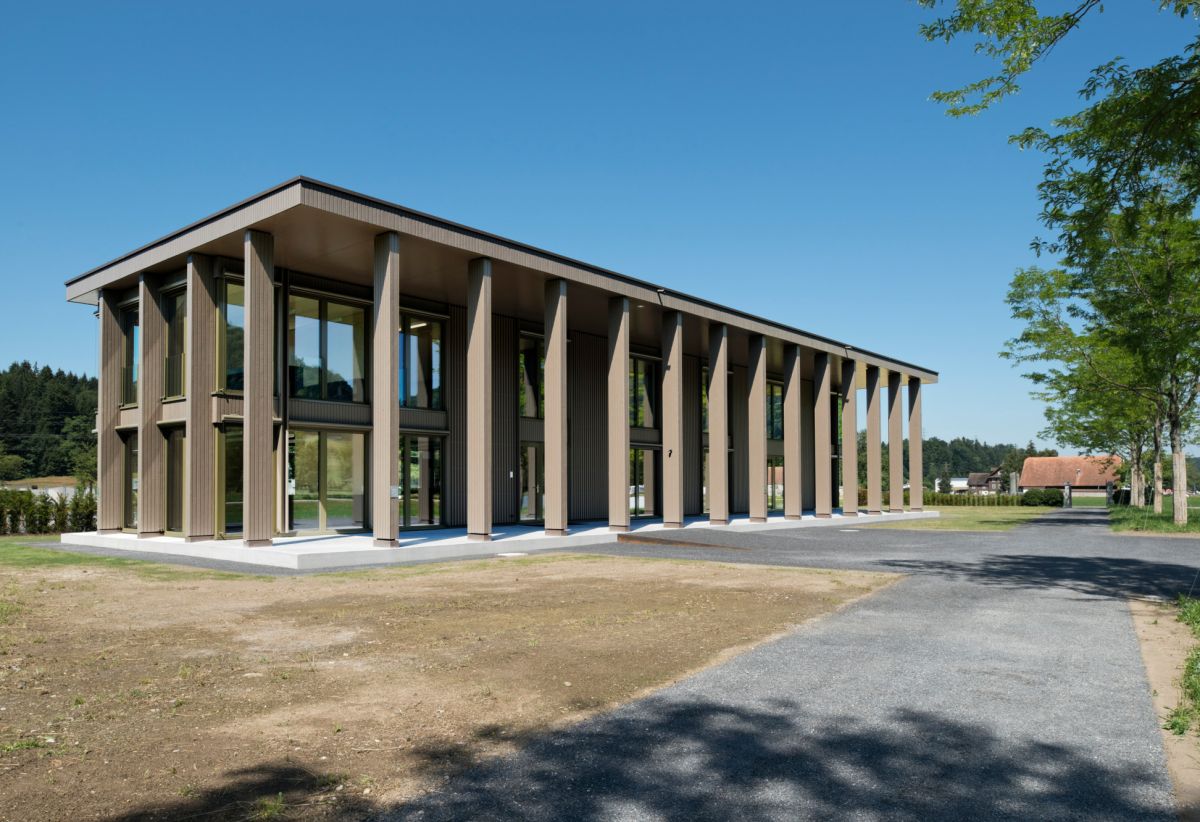 Bâtiment administratif de deux étages avec un toit plat prolongé pour servir d’avant-toit surdimensionné et offrir ainsi de l’ombre aux deux étages.