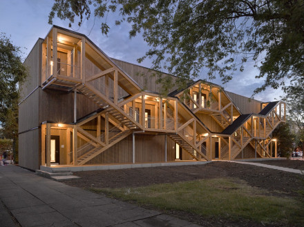 Bâtiment scolaire modulaire à Bienne de l'extérieur avec escalier extérieur éclairé dans une ambiance de soirée.