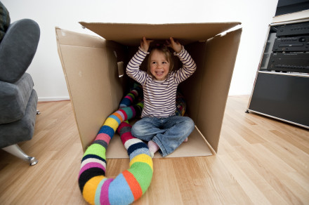 Fille, assise dans un grand carton