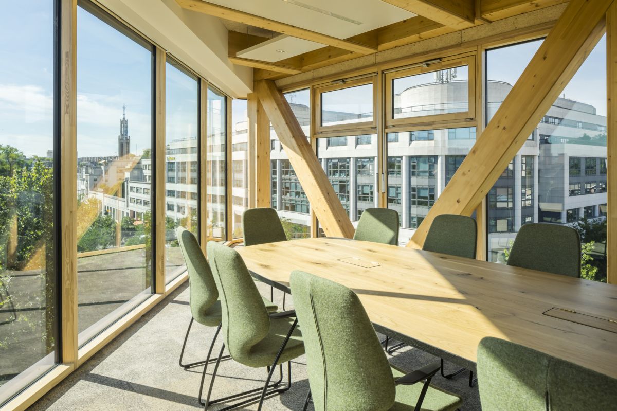 Salle de conférence avec poteaux en bois et larges fenêtres à cadre en bois allant du sol au plafond