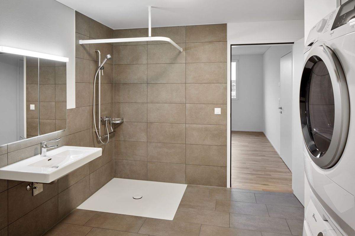 Salle de bain avec douche sans obstacle et colonne lavabo