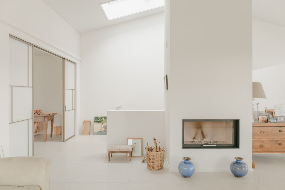 Soggiorno con camino e lucernario e vista sullo studio, che può essere chiuso con sottili porte scorrevoli.