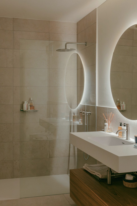 Bagno con doccia arcobaleno e specchio rotondo retroilluminato