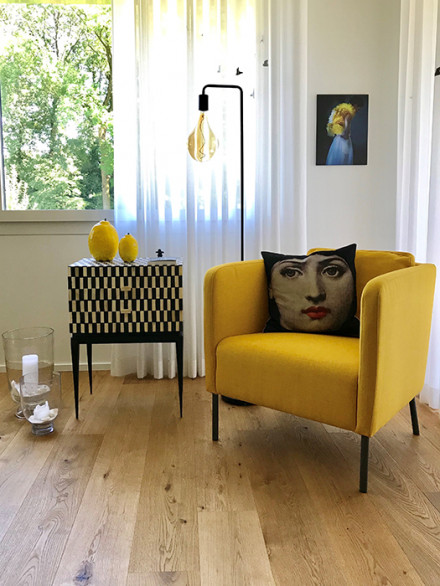 Poltroncina color oro con tavolino e lampada a stelo nel soggiorno