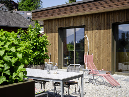 Terrasse de jardin avec gravier, meubles de jardin et façade en bois